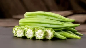 Fresh okra pods and sliced okra on a surface