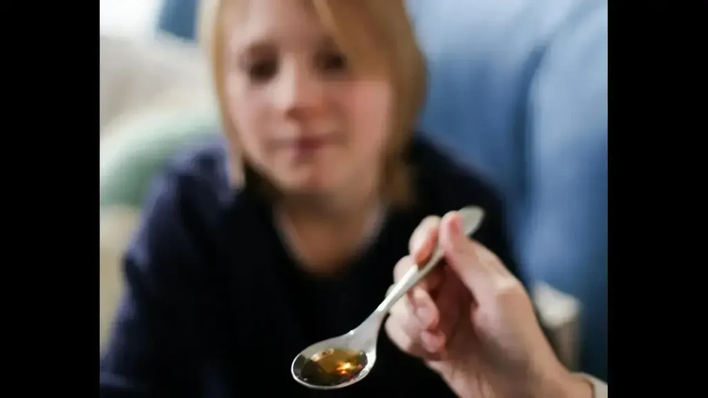 Bottle of syrup and children’s medicine spoon highlighting concerns about misuse of liquid painkiller for kids.