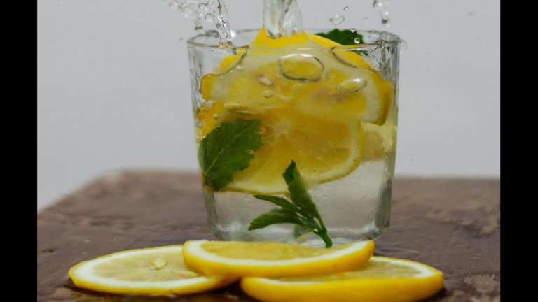 Fresh lemons whole and sliced, on a kitchen surface.
