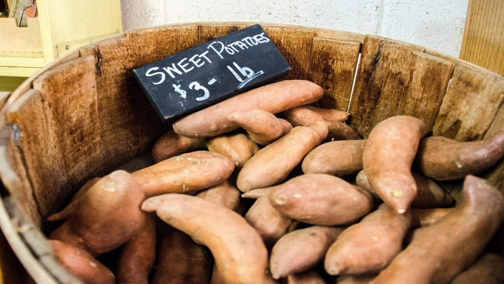Sweet potatoes and carrots side by side on a table.