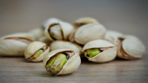 Close-up of pistachio nuts showing green kernels in shells, symbolizing health benefits.