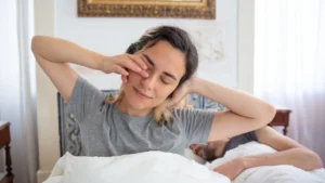 Man sitting on bed after waking up slowly to support heart health after 40