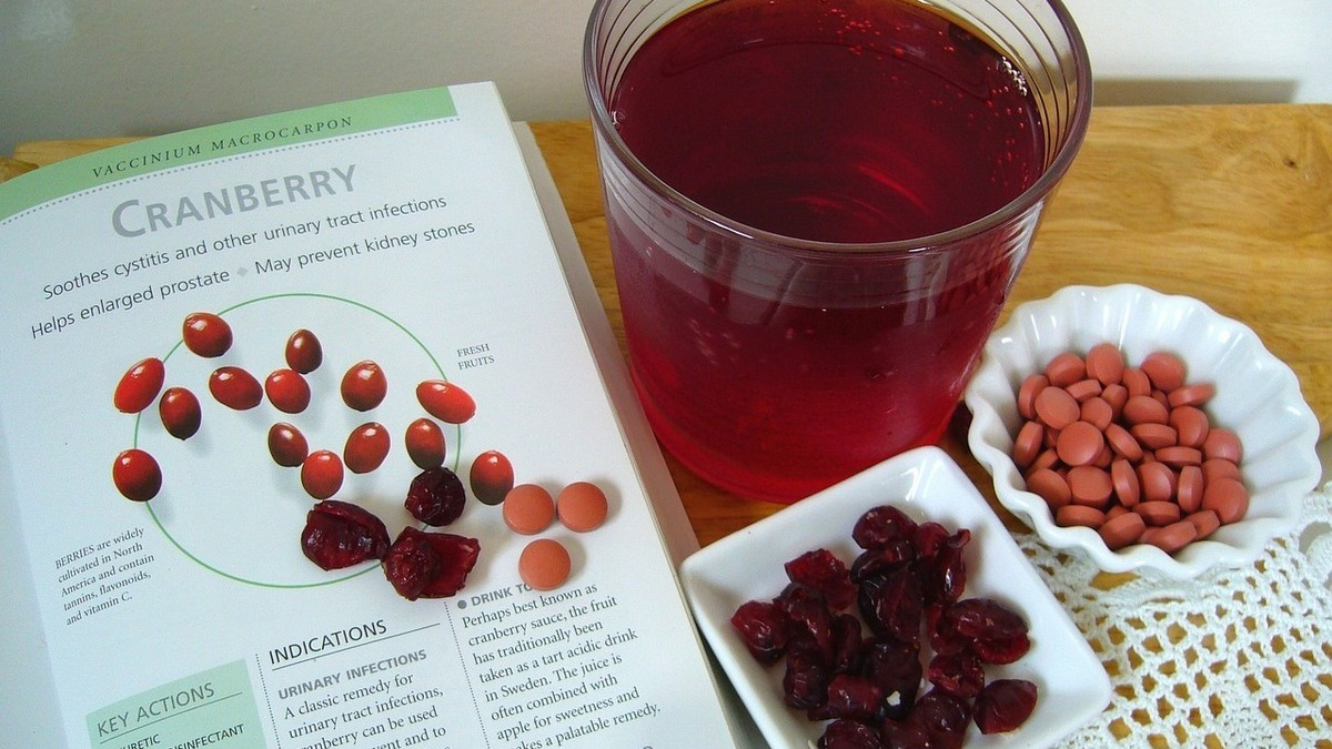 Glass of cranberry juice with fresh cranberries beside it, representing natural support for UTIs and antibiotic resistance research.