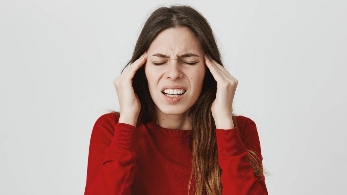 Person suffering from a migraine while using painkillers, illustrating medication overuse headache and rebound headache symptoms.