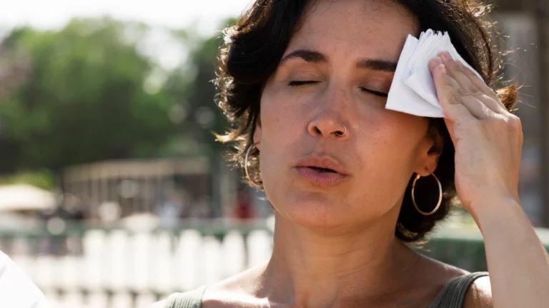 A person drinking water while traveling in extreme heat with medicine tablets placed nearby, showing hydration and medication safety awareness