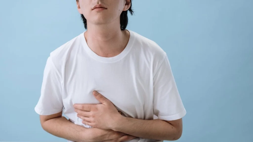 Person experiencing stomach bug symptoms while learning how long norovirus remains contagious and how it spreads.
