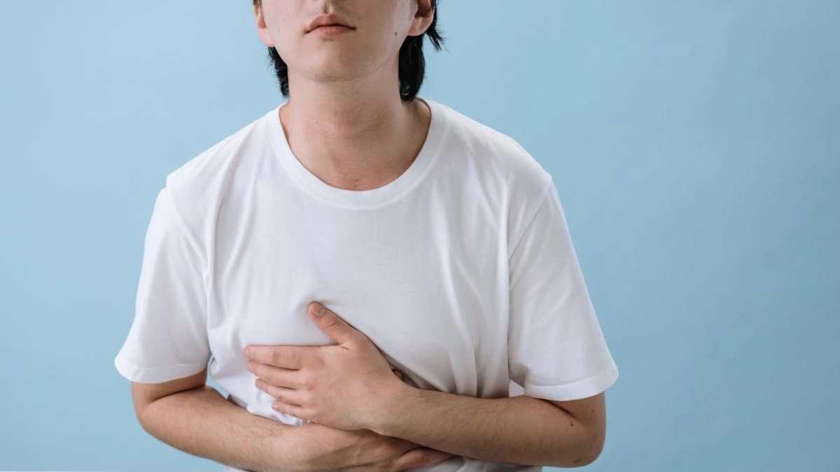 Person experiencing stomach bug symptoms while learning how long norovirus remains contagious and how it spreads.