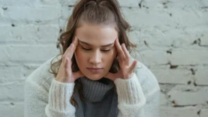 Woman experiencing a migraine with aura while reviewing birth control options, highlighting the connection between hormonal contraception and stroke risk.