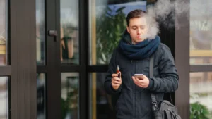 Person holding a nicotine patch while throwing away a vape device, representing quitting vaping and nicotine addiction recovery with nicotine replacement therapy support.