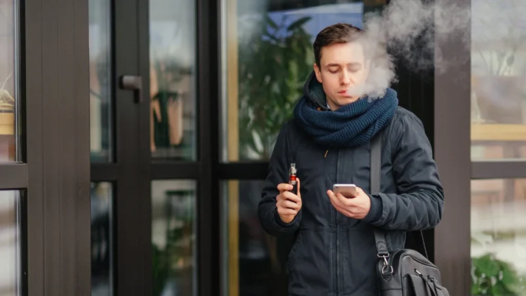 Person holding a nicotine patch while throwing away a vape device, representing quitting vaping and nicotine addiction recovery with nicotine replacement therapy support.