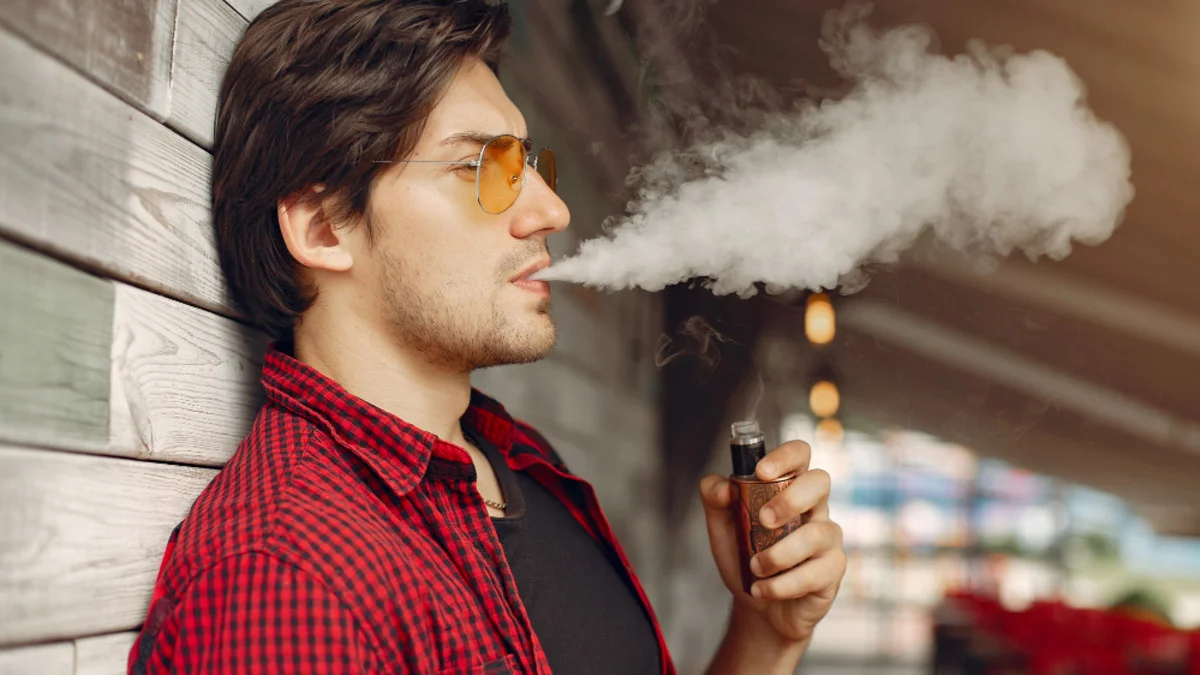Person holding an e-cigarette beside a skeletal X-ray, illustrating the potential impact of vaping on bone density, fracture risk, and osteoporosis.