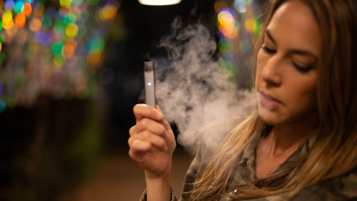 Cigarette and vape device placed side by side showing the comparison between smoking and vaping risks