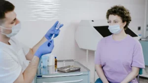 Patient watching a healthcare worker open a sealed sterile syringe before an injection
